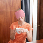 360° Massage Migraine Relief pink gel eye mask with full head coverage worn by a smiling woman holding a white cup