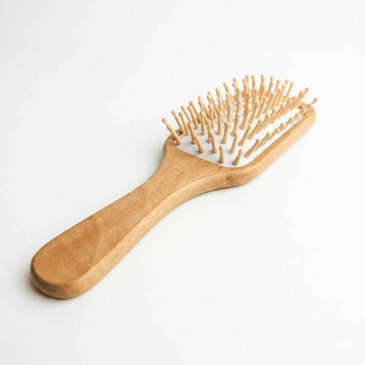 Eco-Friendly Bamboo Paddle Brush with natural wood handle, flexible cushion base, and rounded bamboo bristles for gentle detangling.