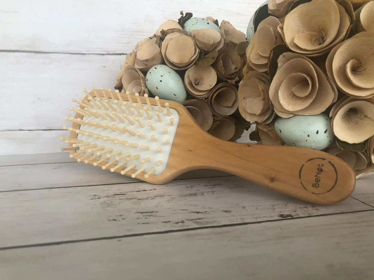 Eco-friendly bamboo paddle brush with natural wooden bristles for gentle detangling and scalp massage