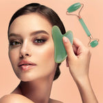 Gua Sha Board and facial roller set in green natural resin held against a woman's cheek for skincare massage