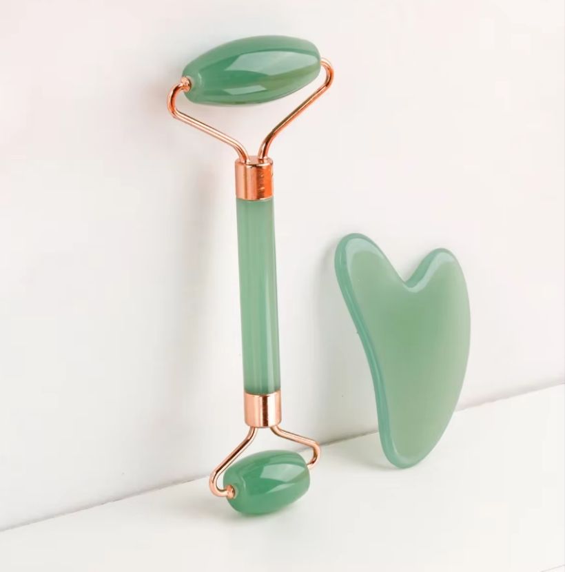 Gua Sha Board and facial roller set in smooth green natural resin with contoured edges and polished finish for massage.