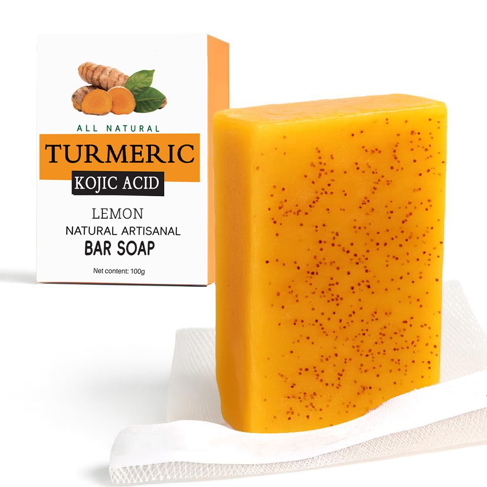 Natural Turmeric Soap bar in bright yellow with small dark exfoliating specks, shown next to its white and orange lemon-scented box packaging.
