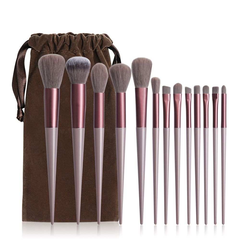 13-Piece Makeup Brush Set with soft synthetic bristles, rose gold and beige handles, includes large to small face and eye brushes with a brown drawstring pouch.