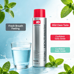 Silver and red bottle of Stain Removing Mouthwash next to a glass of clear blue liquid with mint leaves around