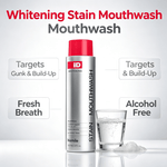 Silver and red bottle of Stain Removing Mouthwash labeled alcohol free with fresh breath benefits alongside a glass of clear mouthwash liquid and foam.